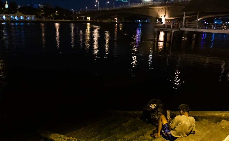 A man rests under the Memorial Bridge, which spans the Chao Phraya River in Bangkok.