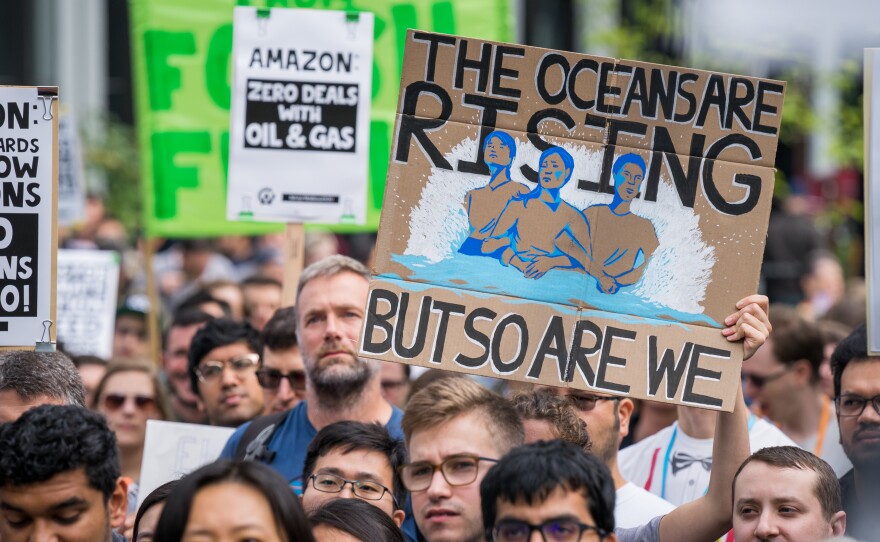 A protester holds a sign reading "The Oceans Are Rising But So Are We" at an Amazon employee walkout in Seattle, as part of the Global Climate Strike on Sept. 20, 2019. At some companies, employees are putting increasing pressure on their bosses to act on climate change.
