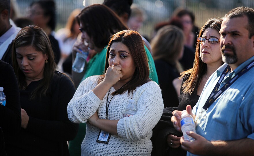 Workers wait to be evacuated by bus as police search for suspects.