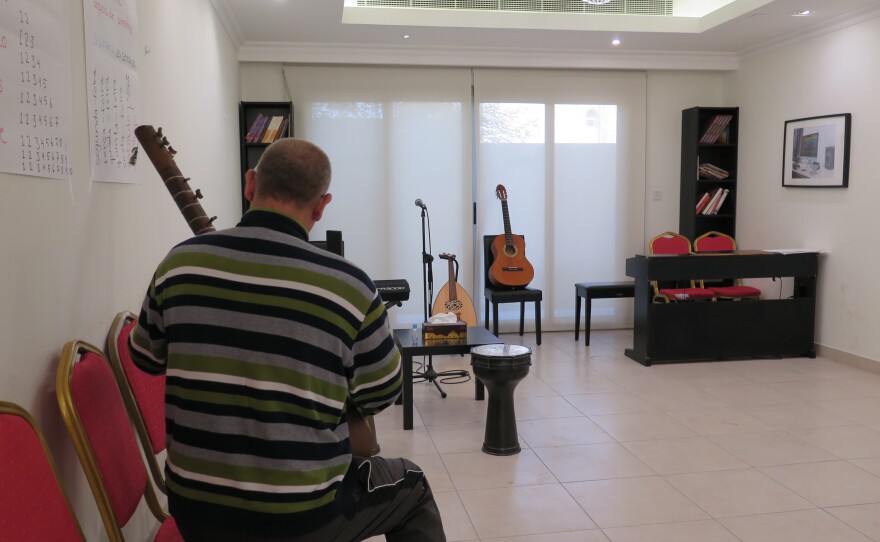 Basir, an <em>ustad</em> or master musician and teacher, holds a tanbur. He had to leave all his own instruments behind when he fled Kabul. He hid his guitars and tanbur in a water tank on the roof of his house.