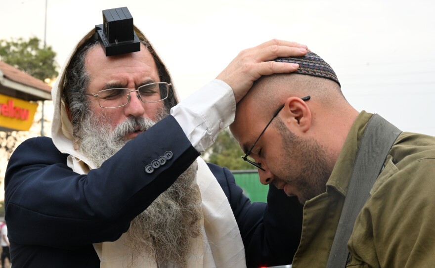 A religious Jewish man offers soldiers blessings and prayers.