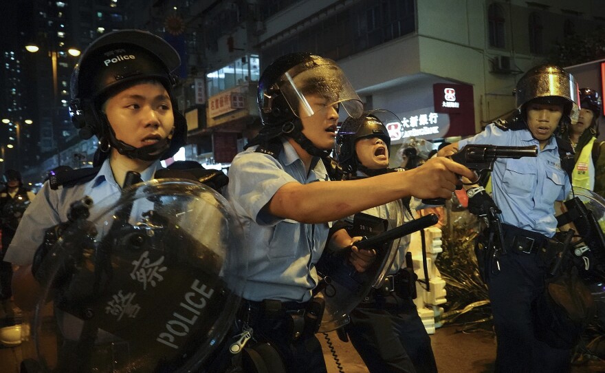 Policemen pull out their guns after a confrontation with demonstrators during a protest in Hong Kong, on Sunday. One officer fired a warning shot in the air — the first such incident in 11 weeks of protests.