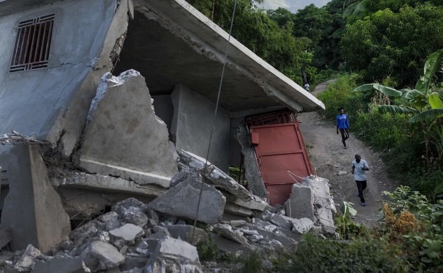 <strong data-stringify-type="bold">Mon., Aug. 16: </strong>People walk past a collapsed building in Saint-Louis-du-Sud, Haiti.