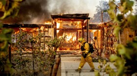 Woodbridge firefighter Joe Zurilgen passes a burning home as the Kincade Fire rages in Healdsburg, Calif., on Sunday, Oct 27, 2019. 