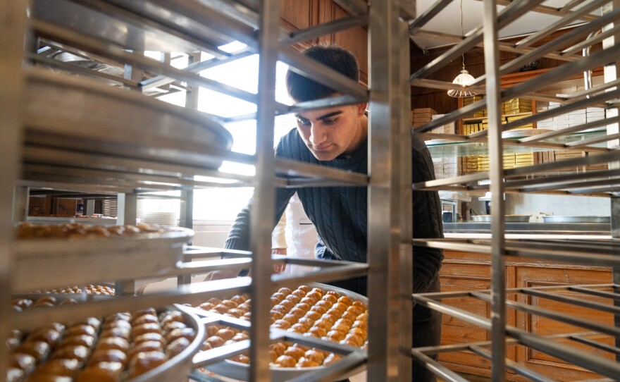 An employee moves fresh baklava onto racks in the front of the restaurant at Imam Cagdas.