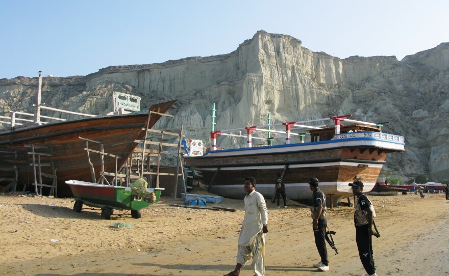 Boat building on the beach at Gwadar, watched over by anti-terrorism commandos. Separatists carry out periodic attacks in Balochistan, the province in southwestern Pakistan.