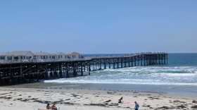 People enjoy the beach as other walk along Crystal Pier in Pacific Beach, San Diego on July 7, 2025.
