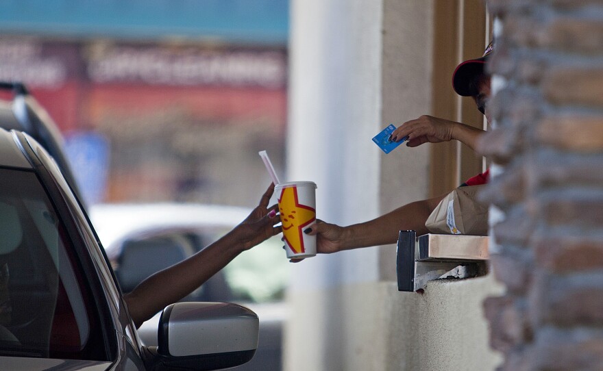 A Carl's Jr. employee serves a customer through a drive-thru window in San Diego on Sept. 13, 2013.