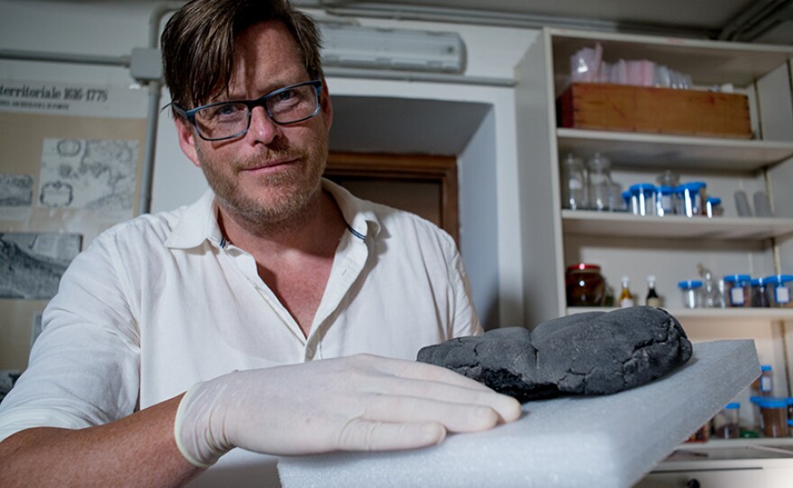 Kevin Dicus, University of Oregon, holding a 2000 year-old bread. Professor Dicus’ primary interest is the archaeology of Italy during the mid-to late-Republican period.