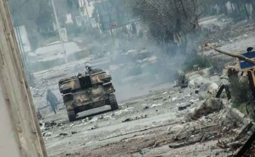 A government tank drives through ruined Homs.