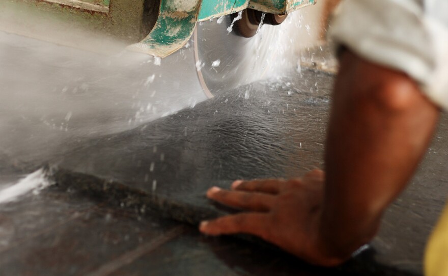 A worker cuts black granite to make a countertop. Though granite, marble and "engineered stone" all can produce harmful silica dust when cut, ground or polished, the artificial stone typically contains much more silica, says a CDC researcher tracking cases of silicosis.