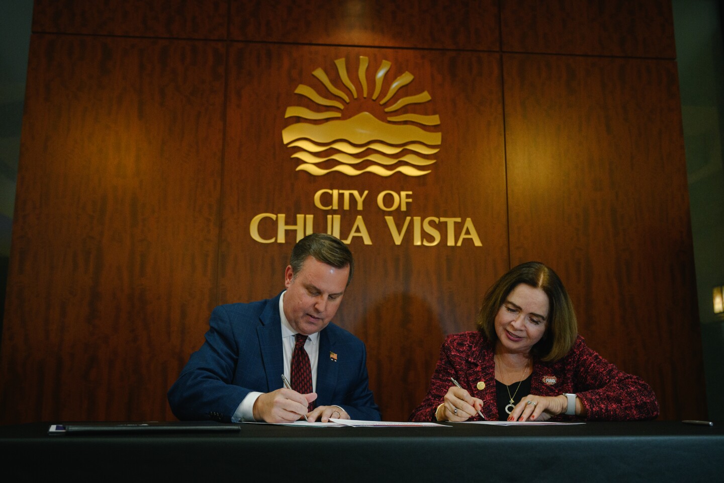 Chula Vista Mayor John McCann, left, signs an agreement with San Diego State University President Adela de la Torre on Dec. 11, 2024.