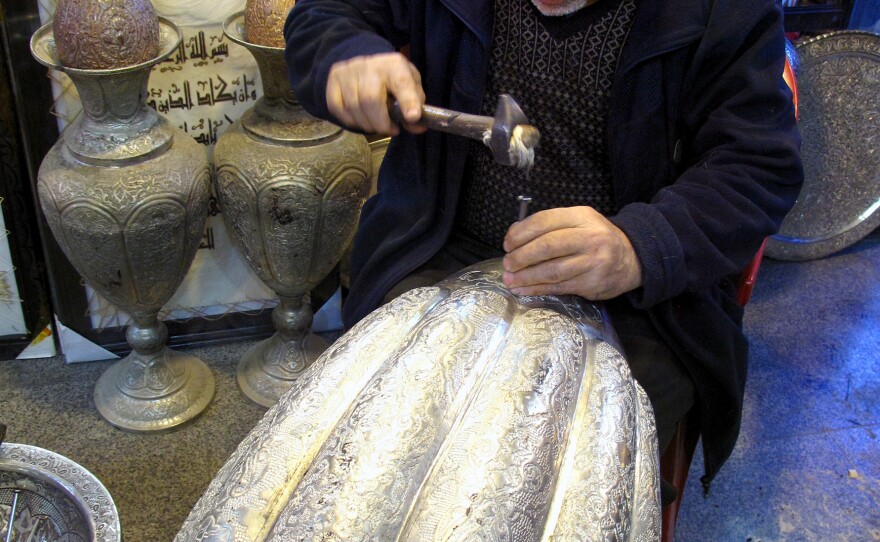 Asghar Pourheydar-Shirazi uses a hammer and a nail to engrave intricate patterns on a vase at his shop in Isfahan. He was optimistic following the country's 1979 revolution, but says the economy has fared poorly for decades. At 64, he works 10 to 12 hour days.