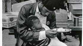 Black Panther feeding son at Free Huey rally, Oakland, 1968