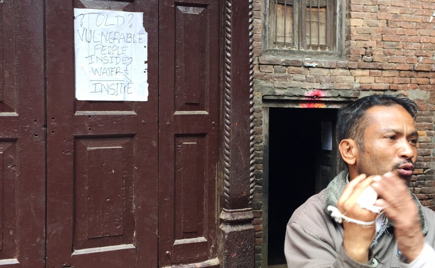 A man stands next to a homemade sign pleading for help in the ancient city of Bakhtapur, which was devastated by the earthquake.
