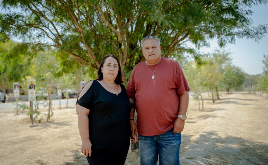 Meir and Kati Zohar hold hands as they pose for a portrait beneath a tree at the Nova music festival memorial site in southern Israel on Sept. 24, 2026. Their daughter, Bar Zohar, was killed during the Hamas-led assault on the festival on Oct. 7, 2023.