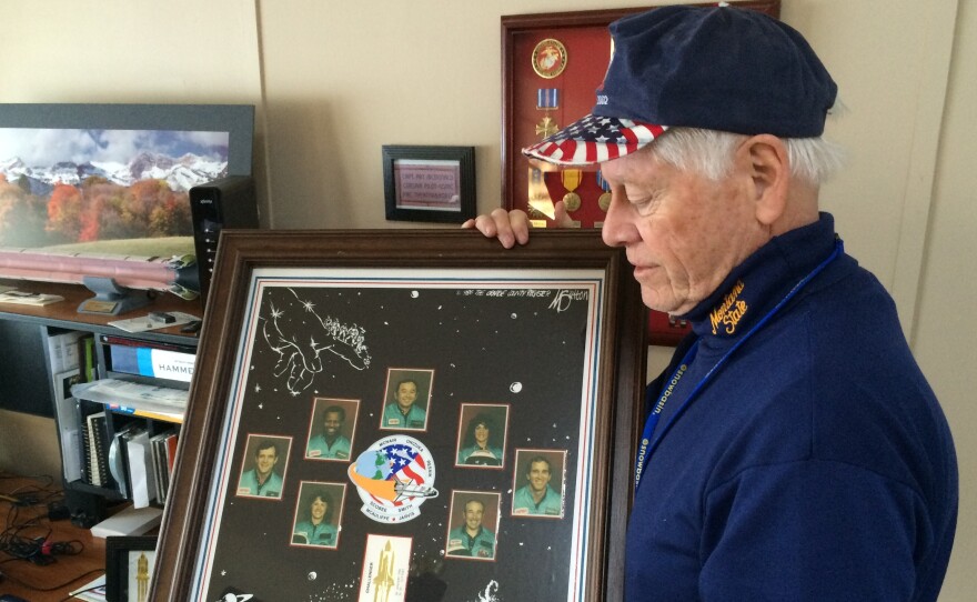 Allan McDonald in 2016 with a commemorative poster honoring the seven astronauts killed aboard the space shuttle Challenger, and McDonald's attempt to postpone the launch.