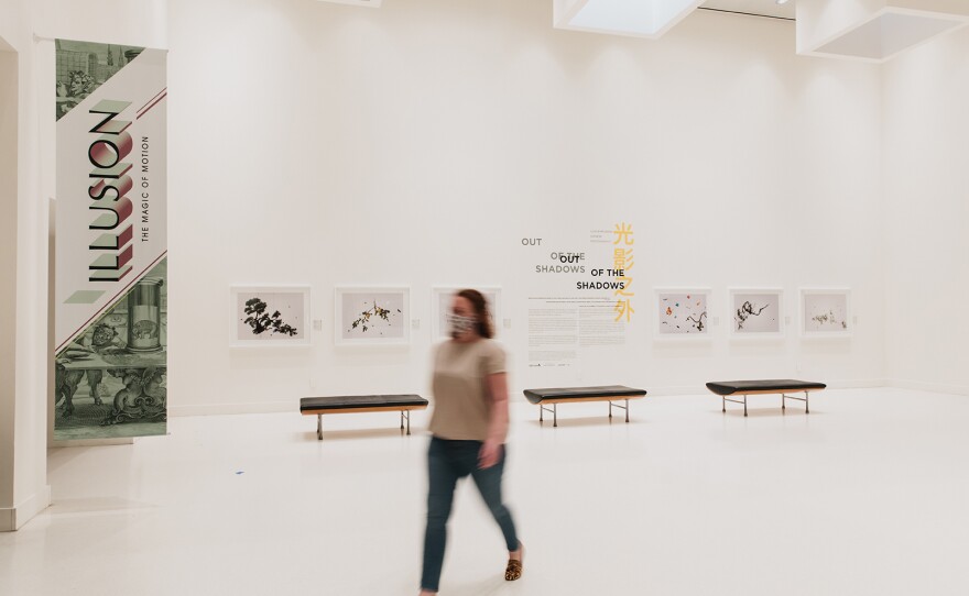 An individual wearing a mask walks past a portion of the "Out of the Shadows: Contemporary Chinese Photography" exhibition at MOPA in July, 2020.