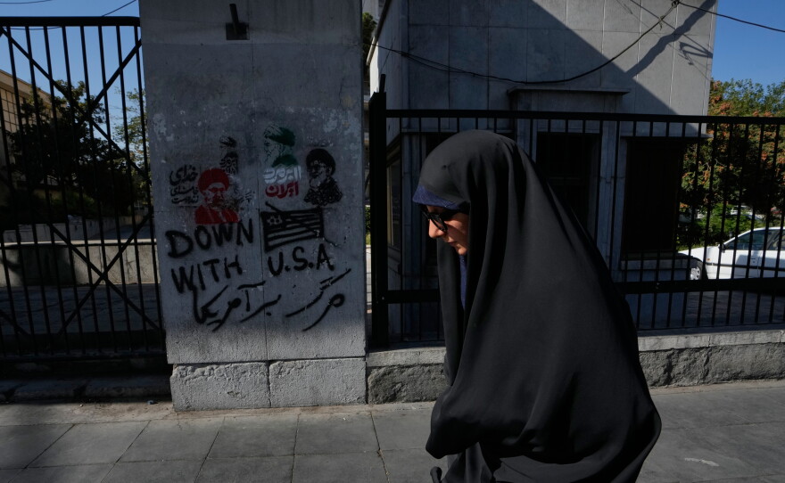 A woman walks past anti-U.S. graffiti and images depicting the late Iranian Supreme Leader Ayatollah Ali Khamenei painted on a wall along Islamic Revolution street in downtown Tehran, Iran, on Aug. 29.
