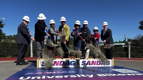 Officials toss dirt with shovels as part of a ceremonial groundbreaking on the University Bikeway, March 11, 2026.