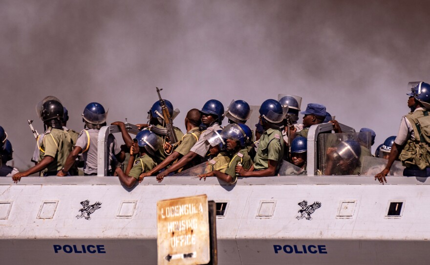 A police truck drives past a thick cloud of smoke as protesters burn tires in Bulawayo, Zimbabwe, during a tense, three-day nationwide protest against a fuel price hike in January.