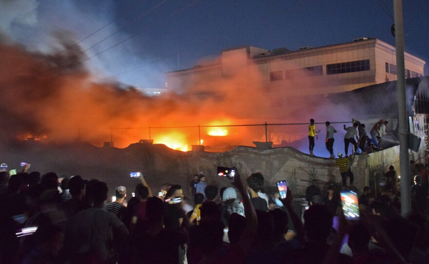 People gather as a massive fire engulfs the coronavirus isolation ward of Al-Hussein hospital in the southern Iraqi city of Nasiriyah, late on July 12, 2021.