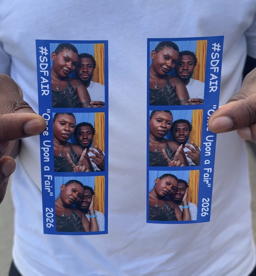 Audy McAfee's partner, Miles Price, holds photo booth strips of the couple at the San Diego County Fair on June 10, 2026.