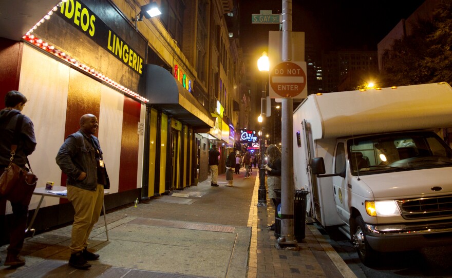 The needle exchange van parks on the corner of a block in Baltimore that is home to numerous strip clubs.