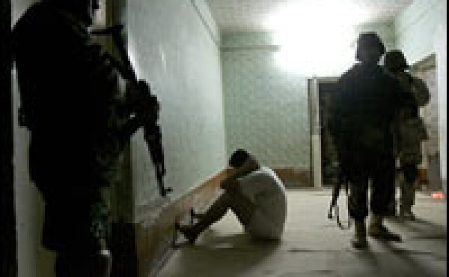 A temporarily detained Iraqi man sits facing a wall as Iraqi Special Police commandos from a unit known as the Wolf Brigade search his house in Ramadi, west of Baghdad, in February 2006.