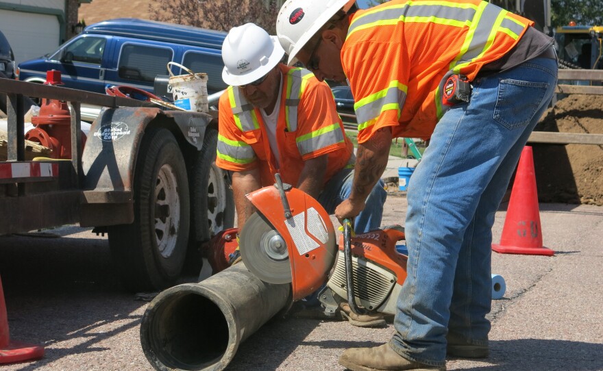Construction workers prepare to cut a pipe for a new infrastructure project for the Security, Colo., Water and Sanitation District. The project is needed to ensure drinking water is 100 percent PFC free.