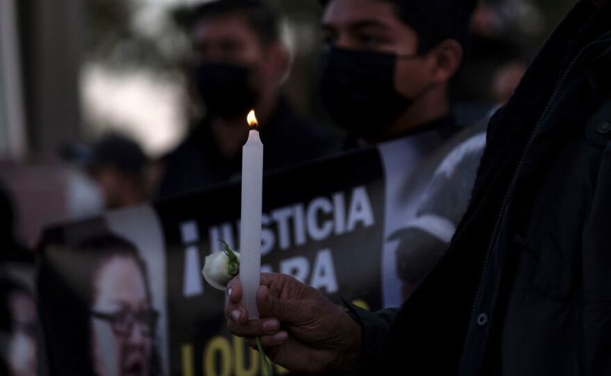 A person holds a rose and a candle as journalists and supporters protest the murders of their colleagues Lourdes Maldonado and Margarito Martinez, in front of the federal prosecutors building in Tijuana.
