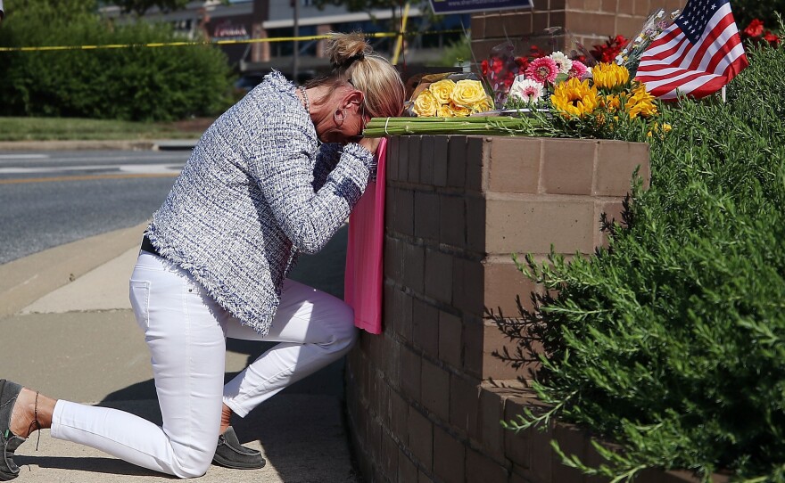 Lynne Griffin pays her respects at a makeshift memorial outside the Capital Gazette offices, one day after a gunman killed five people in its newsroom. Griffin was a journalism student under John McNamara — one of the people killed Thursday.