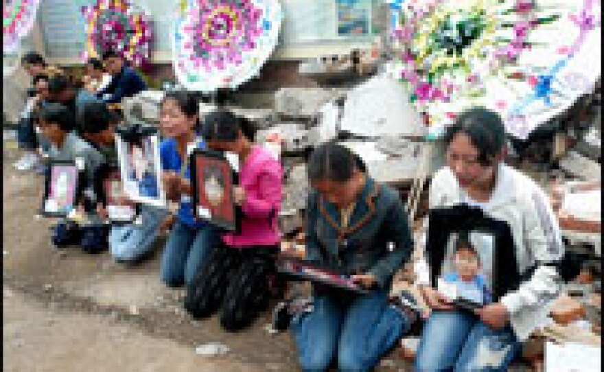 Parents hold pictures of their children who died when a school collapsed last week. Wednesday was the last of three official days of mourning for the earthquake victims.