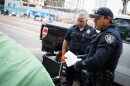 San Diego police give a citation to a woman camping on the sidewalk of Commercial Street in San Diego, Calif. June 9, 2022.