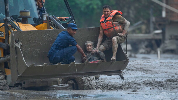 Rescuers use an earthmover to carry a victim of flash flooding to safety along the Trishuli River in Nepal's Nuwakot district, Wednesday, Aug. 26, 2026.