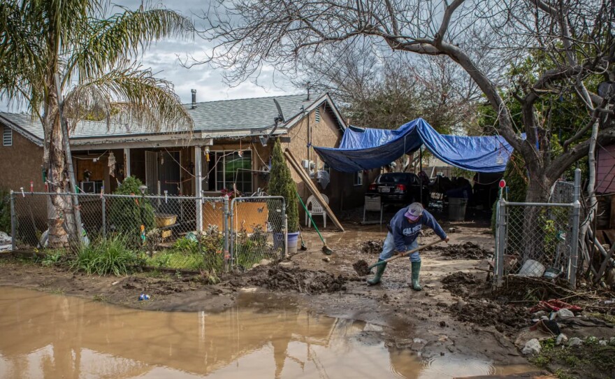 A resident shovels mud deposited by flooding from his driveway in Cutler on March 12, 2023.