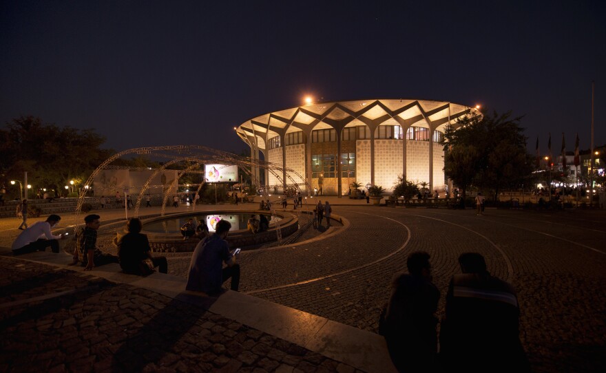 People hang out in the evening outside Tehran's City Theater performing arts center. The economic toll of the sanctions isn't immediately visible in the city.