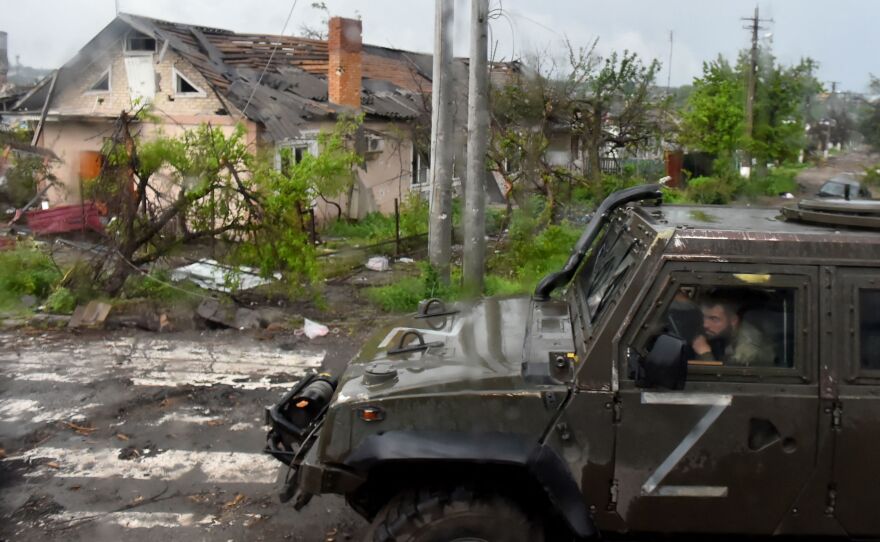 A Russian military vehicle painted with the letter Z drives past destroyed houses in the Ukrainian city of Mariupol on Wednesday.