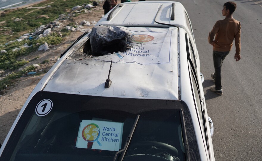 People gather around the wreckage of a car used by the U.S.-based aid group World Central Kitchen on Tuesday after it was hit by an airstrike the previous day in Deir al-Balah in the central Gaza Strip.