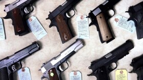 Handguns lined up on a table. 