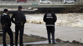 Firefighters monitor the rising Truckee River, Sunday, Jan. 8, 2017, where it runs near the Grand Sierra hotel-casino along a line that divides the cities of Reno and Sparks, Nev.