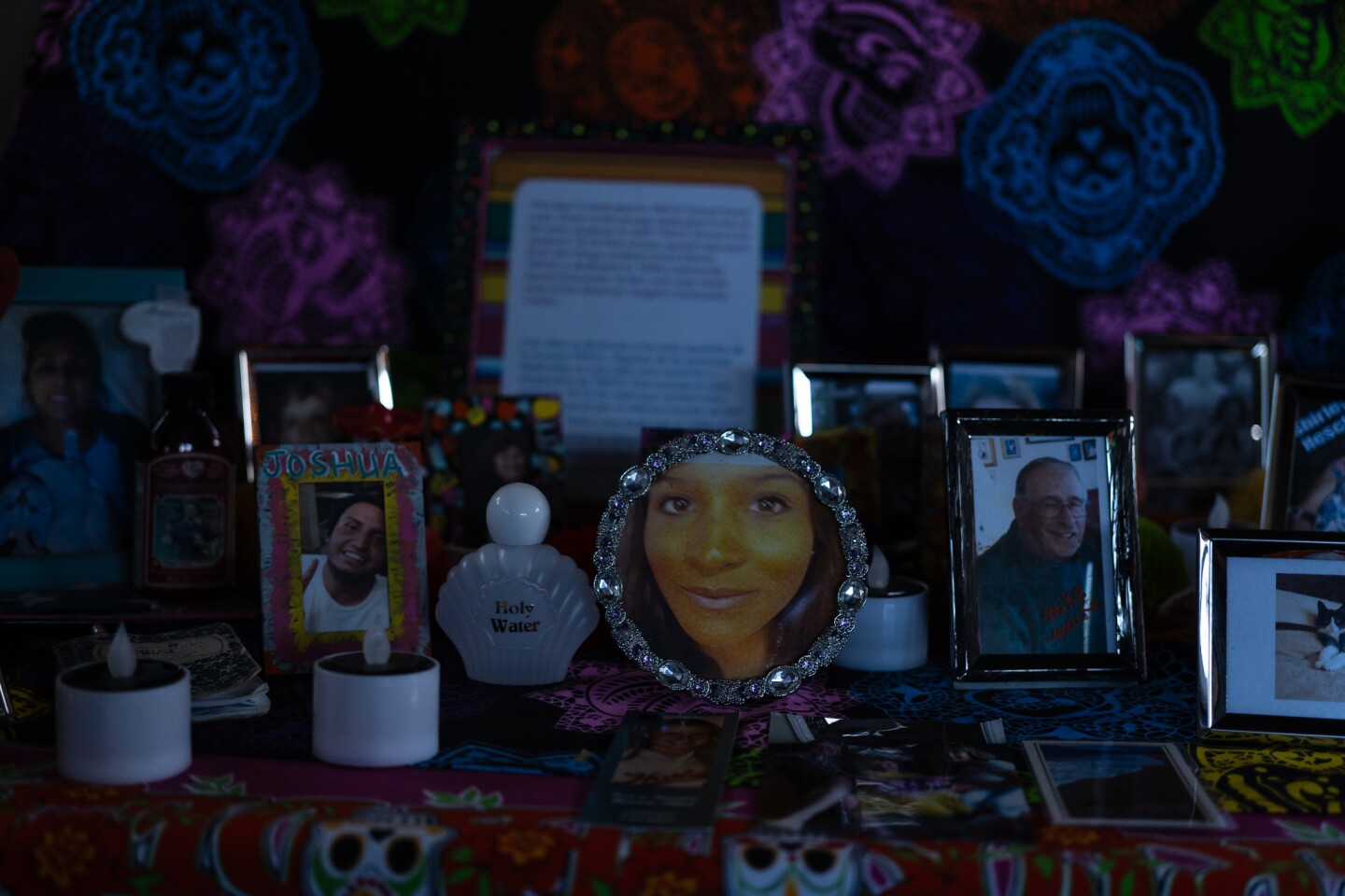 Photos of deceased loved ones, a bottle of Holy Water and electric tea lights adorn an altar inside the Sherman Heights Community Center in San Diego on Oct. 17, 2023.