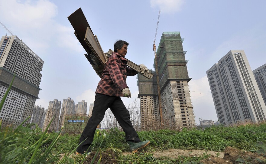 A garbage collector walks past residential and office buildings in construction in Hefei, in China's Anhui province, on April 3. China grew to have the world's second-largest economy in the years since 1989.