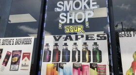 A sign advertising vapes and cigarillos hangs in the window of Fuego Smoke Shop, May 18, 2022.
