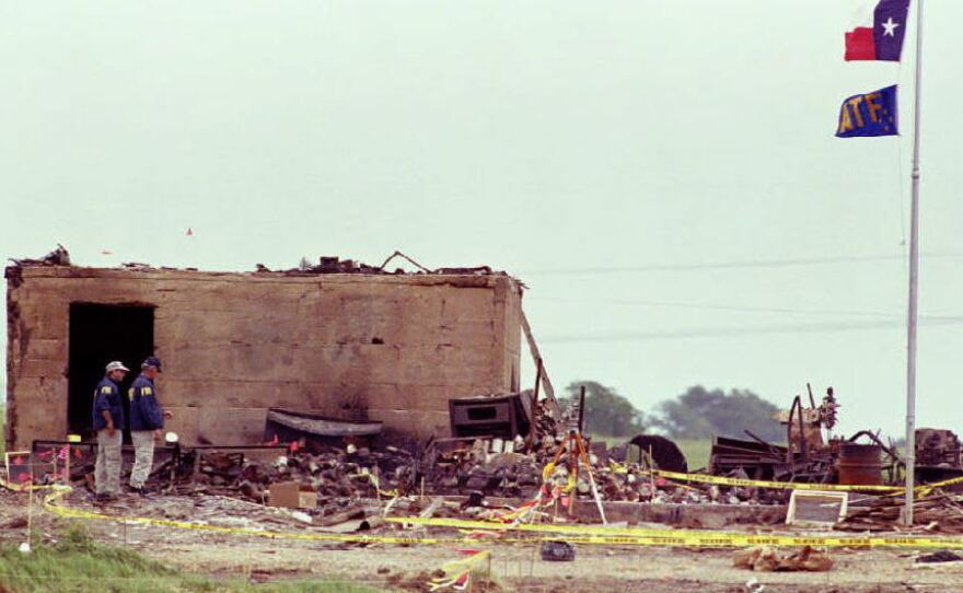 The Texas and Bureau of Alcohol, Tobacco and Firearms flags fly at half-staff over the only structure left standing after a fire destroyed the Branch Davidian compound on April 19, 1993, in Waco, Texas. The blaze ended a 51-day standoff between federal agents and the cult lead by David Koresh.