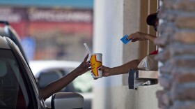 A Carl's Jr. employee serves a customer through a drive-thru window in San Diego on Friday, Sept. 13, 2013.