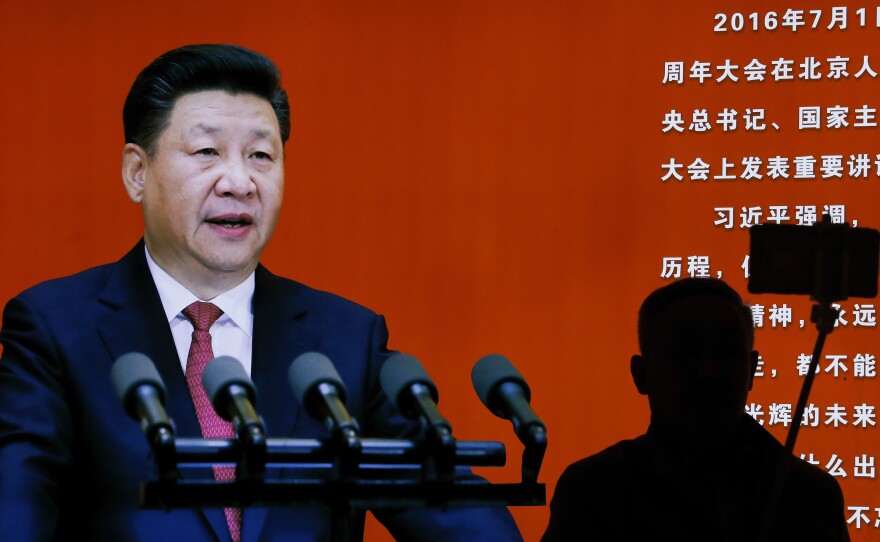 A man takes a selfie near a picture of Chinese President Xi Jinping at an exhibition at a military museum in Beijing on Monday. Xi is expected to use an important meeting this week to re-emphasize his anti-graft campaign. Analysts say the campaign is also used to go after rival factions within the Communist Party.