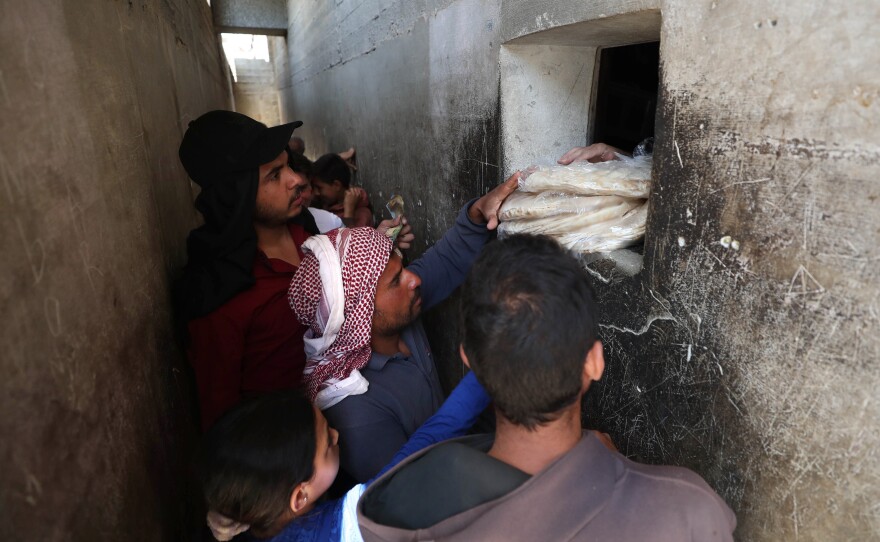 Syrians buy bread at a shop in the town of Binnish in the country's northwestern Idlib province in June. Nowadays, people say they're waiting up to six hours in line for a meager government bread ration.