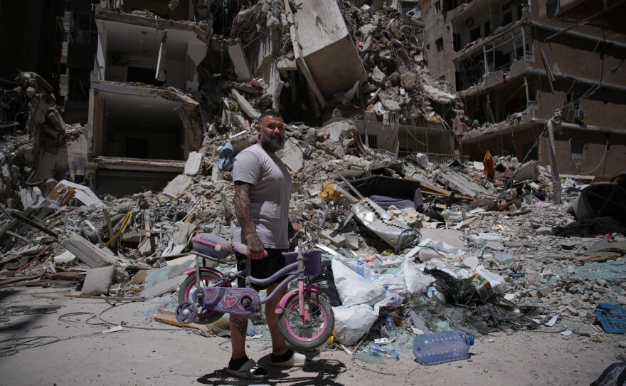 Barber Wissam Srour, 41, holds his daughter's bicycle recovered from his barbershop as he searches for belongings in the rubble of the shop, damaged in an Israeli strike, in the southern port city of Tyre, Lebanon, Friday, June 19, 2026.