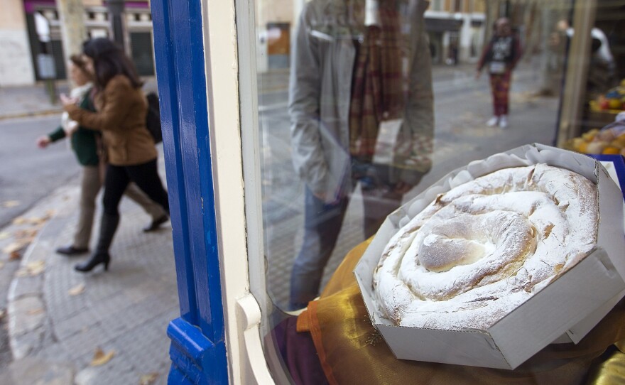 An ensaïmada, a traditional pastry, sits in the front window of a bakery in Palma de Mallorca.